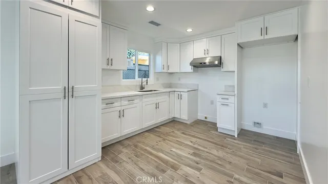 a kitchen with white cabinets and sink