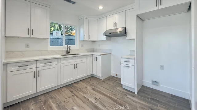 a kitchen with stainless steel appliances a sink cabinets and wooden floor