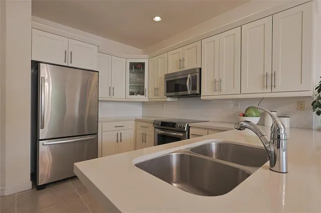 a kitchen with stainless steel appliances granite countertop a refrigerator a sink a stove a microwave and with a refrigerator