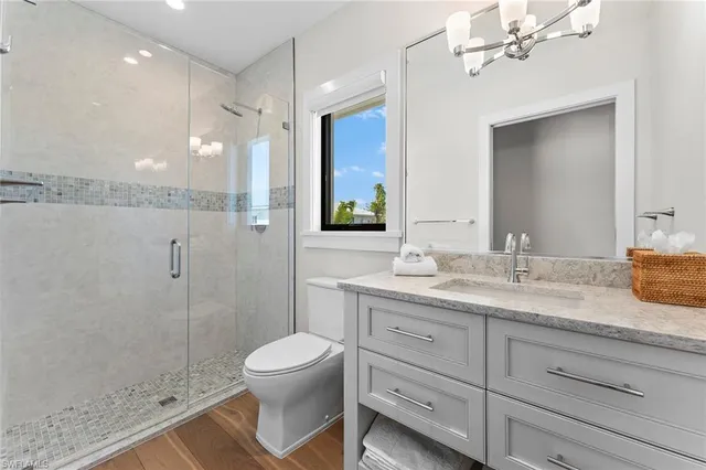 a bathroom with a granite countertop sink a toilet a mirror and shower
