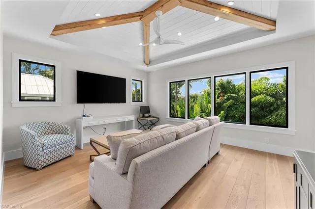 a living room with furniture a flat screen tv and a large window