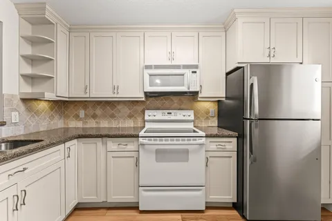 a kitchen with white cabinets and white appliances