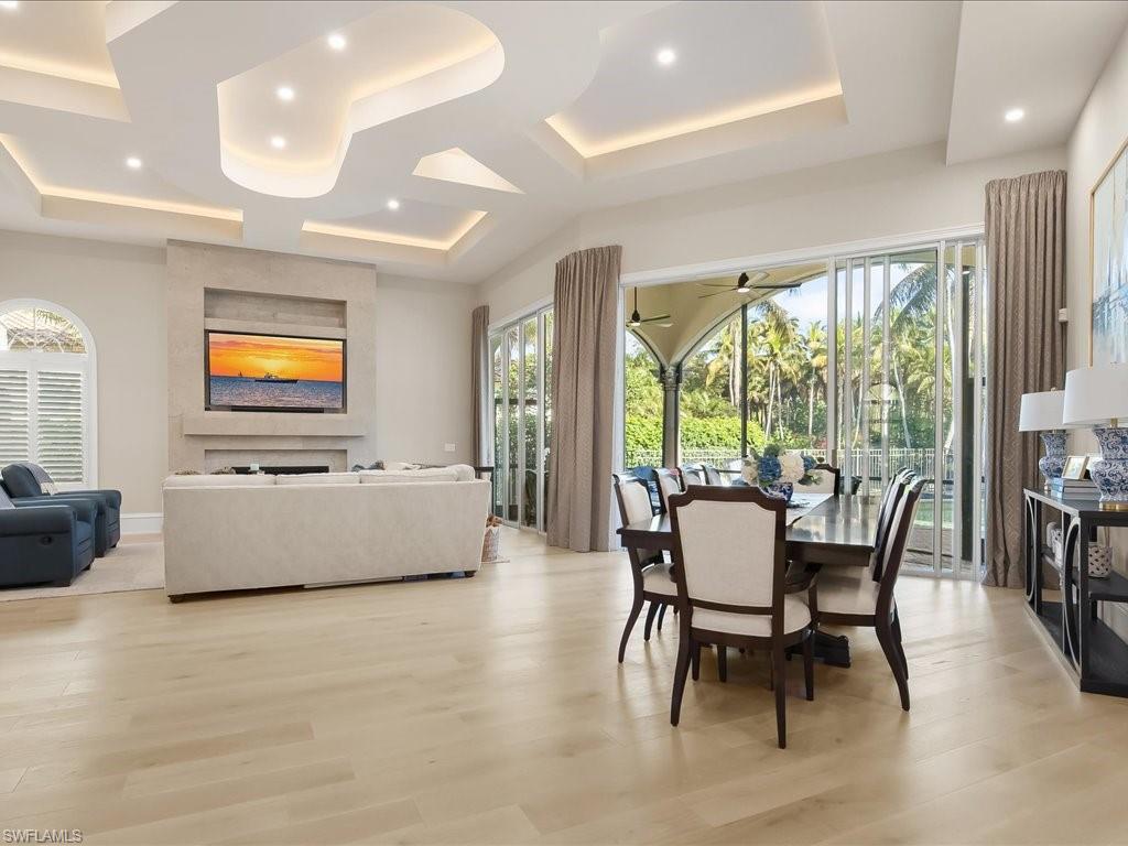 2822 Capistrano Way Naples, FL 34105 - Photo 12 of 47 Dining Area looking into the living room and outside, featuring fireplace, dramatic details in the ceiling and European White Oak wood flooring.