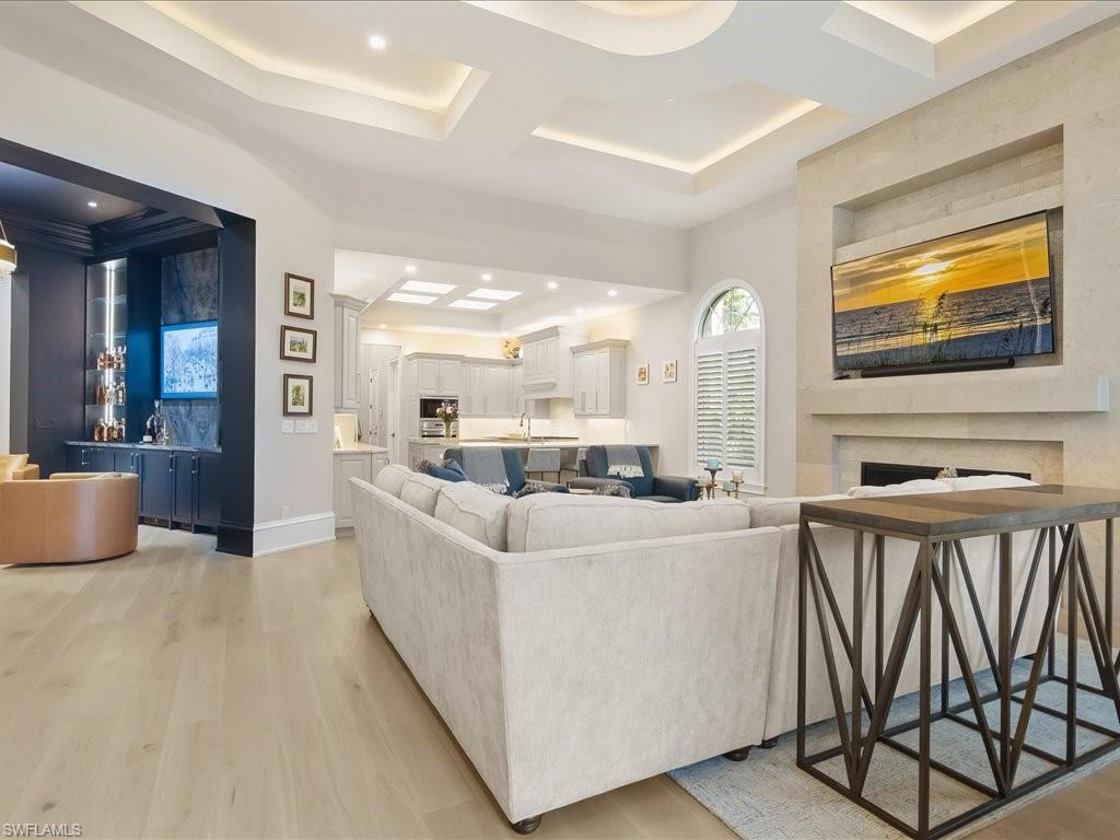 2822 Capistrano Way Naples, FL 34105 - Photo 14 of 47 Living room with fireplace looking into the kitchen and striking bar/cocktail room.