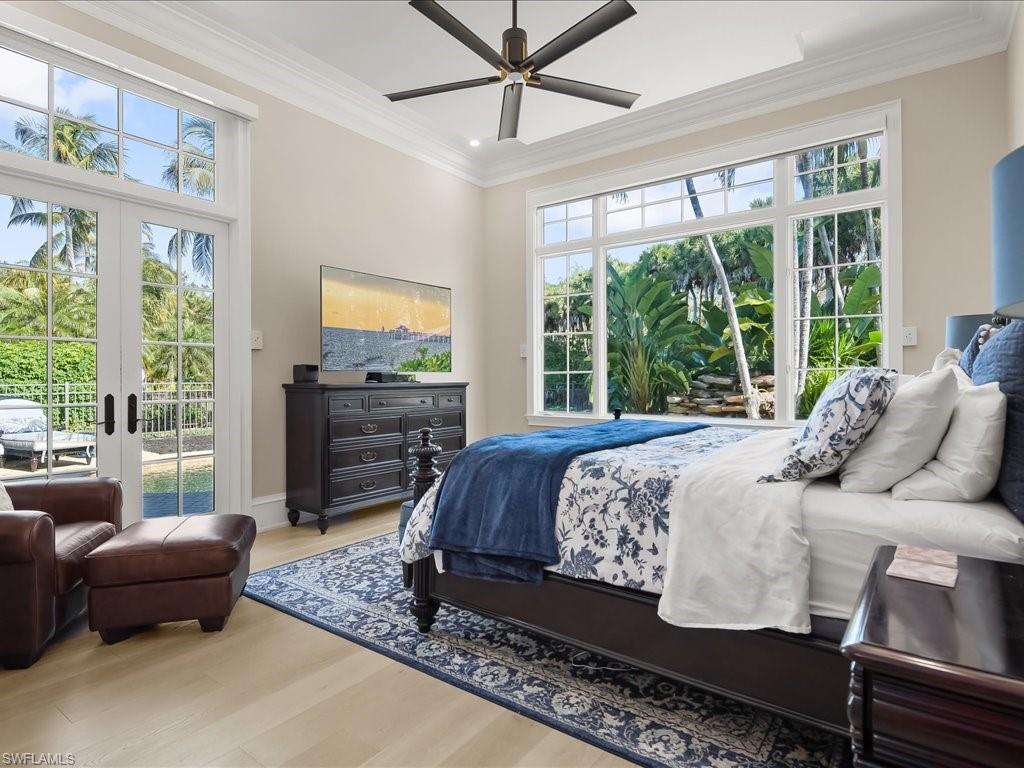 2822 Capistrano Way Naples, FL 34105 - Photo 22 of 47 Primary bedroom suite with french doors to the pool and lovely views of the landscaping and waterfalls.