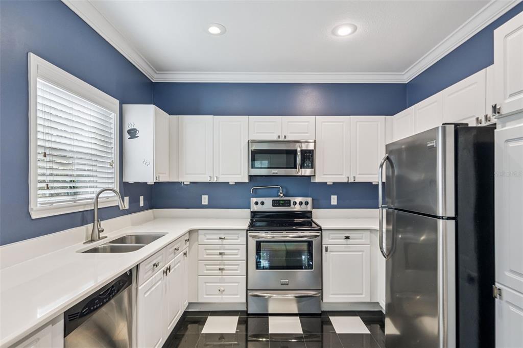 414 Water Street, Unit 414 Celebration, FL 34747 - Photo 12 of 75 a kitchen with white cabinets and stainless steel appliances