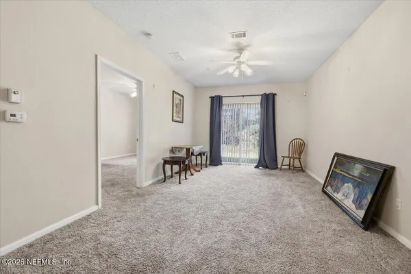 an empty room with chandelier fan and windows