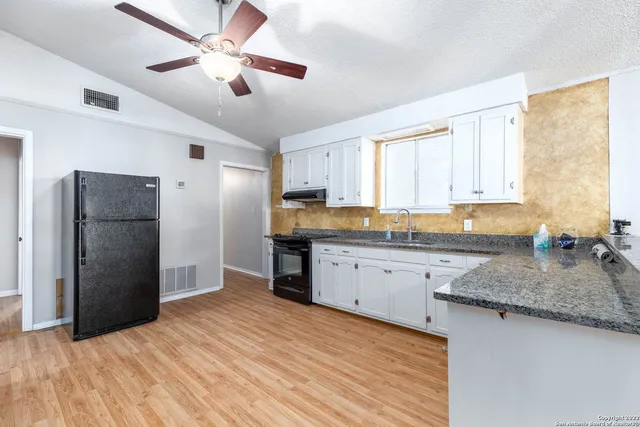 a view of a kitchen with a fridge and wooden floor