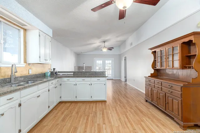 a large kitchen with a wooden floor and white cabinets