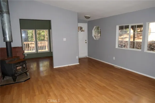 a view of an empty room with window and wooden floor