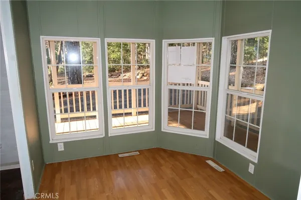 a view of an empty room with wooden floor and windows