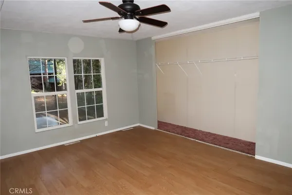 an empty room with windows and ceiling fan