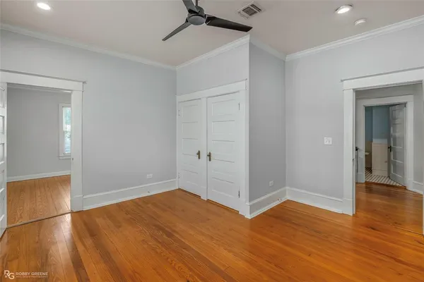 an empty room with wooden floor ceiling fan and windows