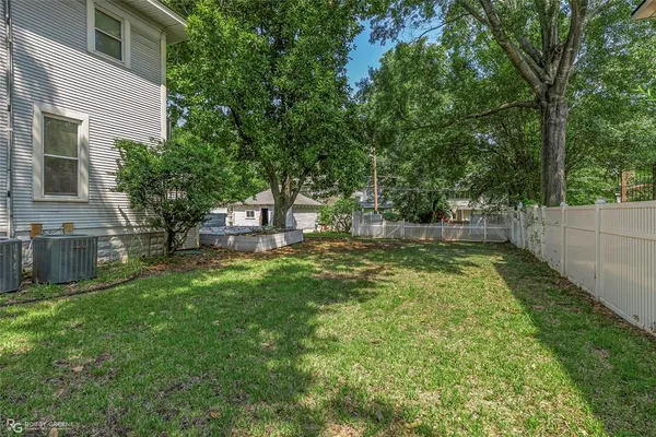 a view of a backyard with a barbeque and large trees