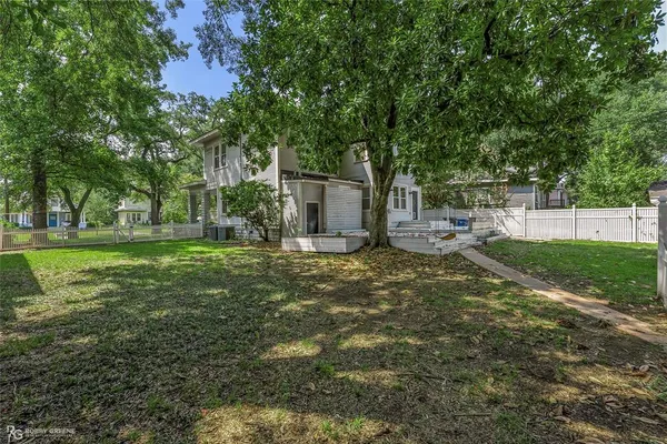 a view of a house with a yard and a large tree