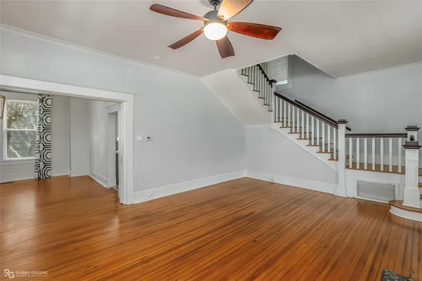 a view of empty room with wooden floor and fan