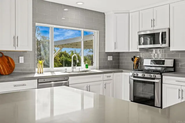 a kitchen with stainless steel appliances granite countertop a stove a sink and a microwave