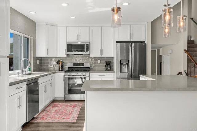 a kitchen with stainless steel appliances granite countertop a refrigerator a stove and a sink