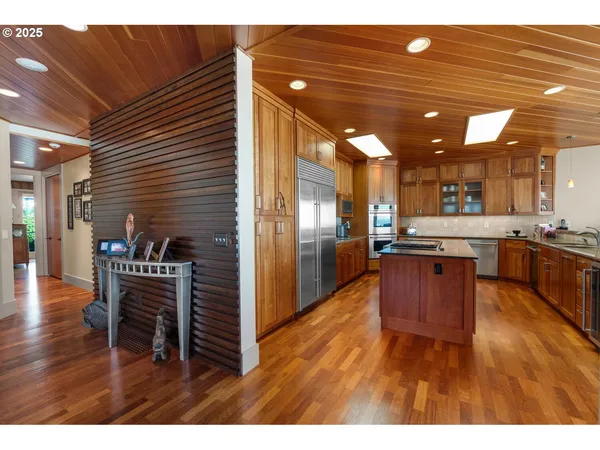 a kitchen with stainless steel appliances kitchen island granite countertop a table chairs and a refrigerator