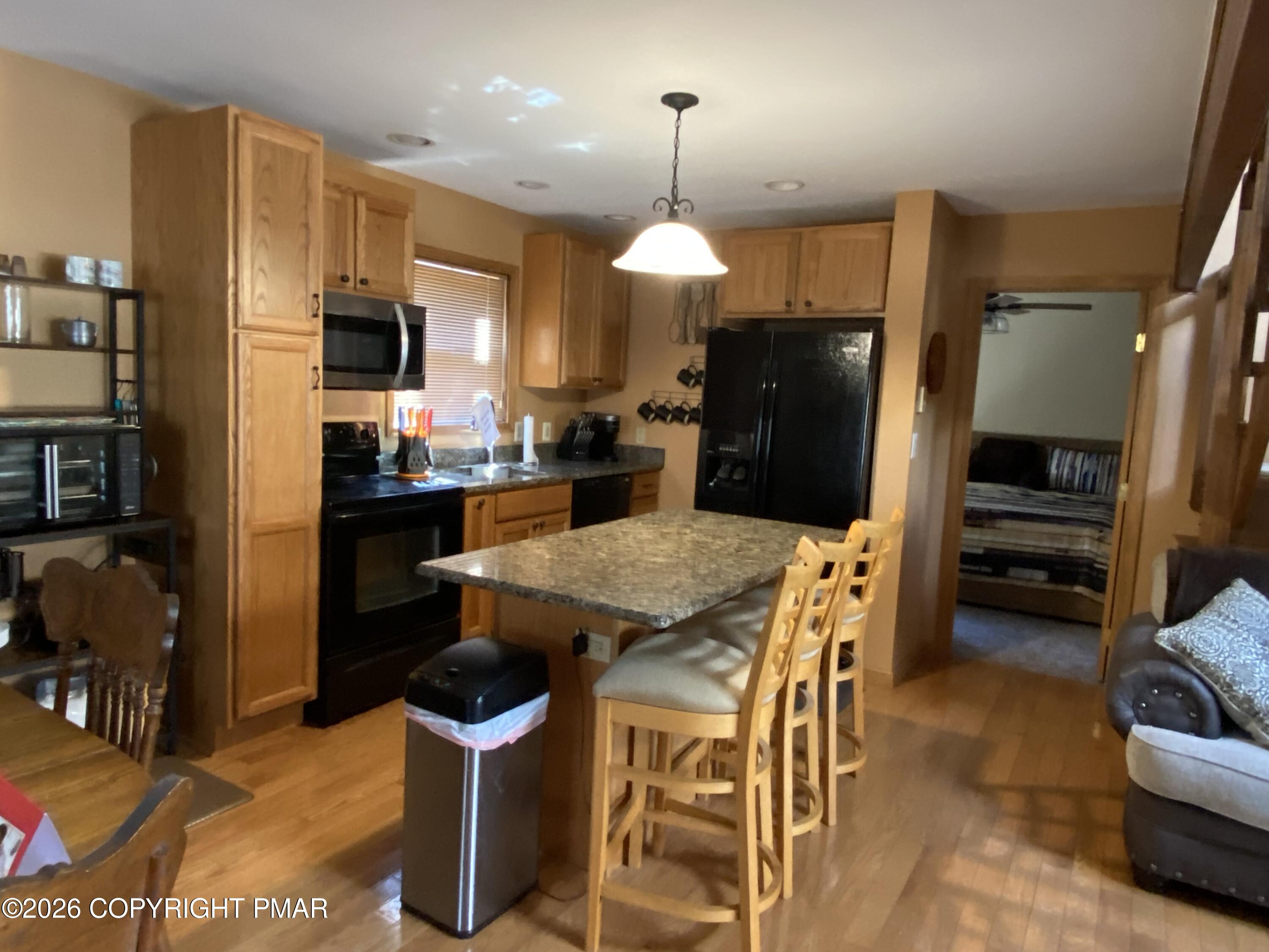 122 Dover Drive Bushkill, PA 18324 - Photo 47 of 49 a kitchen with stainless steel appliances kitchen island granite countertop a refrigerator a stove a sink a dining table and chairs with wooden floor