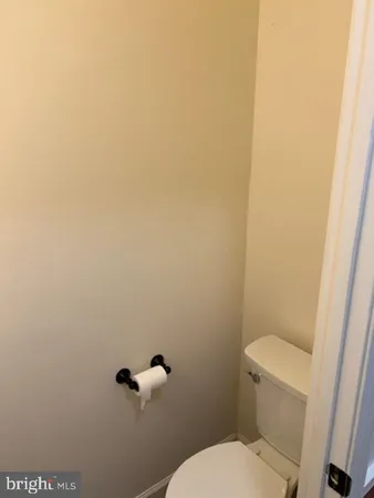 a white toilet sitting next to a white wall