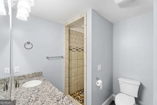 a bathroom with a granite countertop sink a toilet and shower