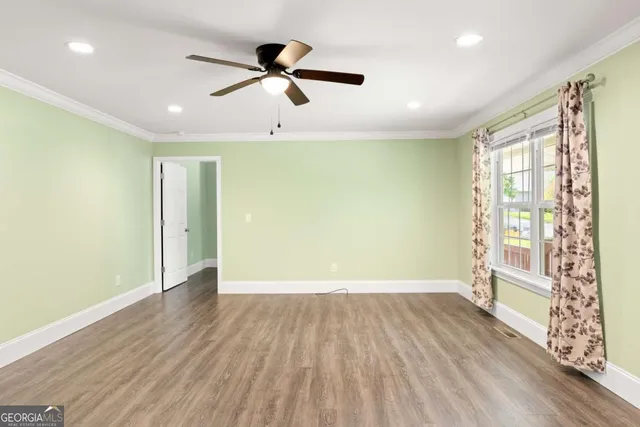 an empty room with wooden floor fan and windows
