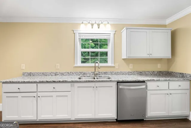 a kitchen with granite countertop white cabinets and a window