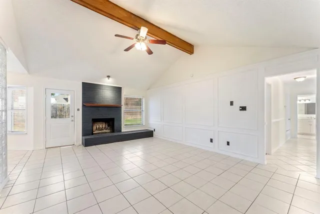 a view of an empty room with a fireplace and a chandelier fan