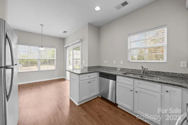 a kitchen with granite countertop white cabinets and wooden floor