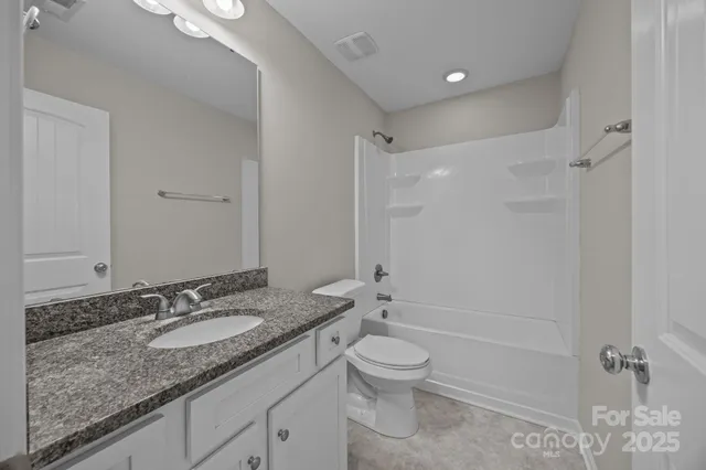 a bathroom with a granite countertop sink a toilet and shower