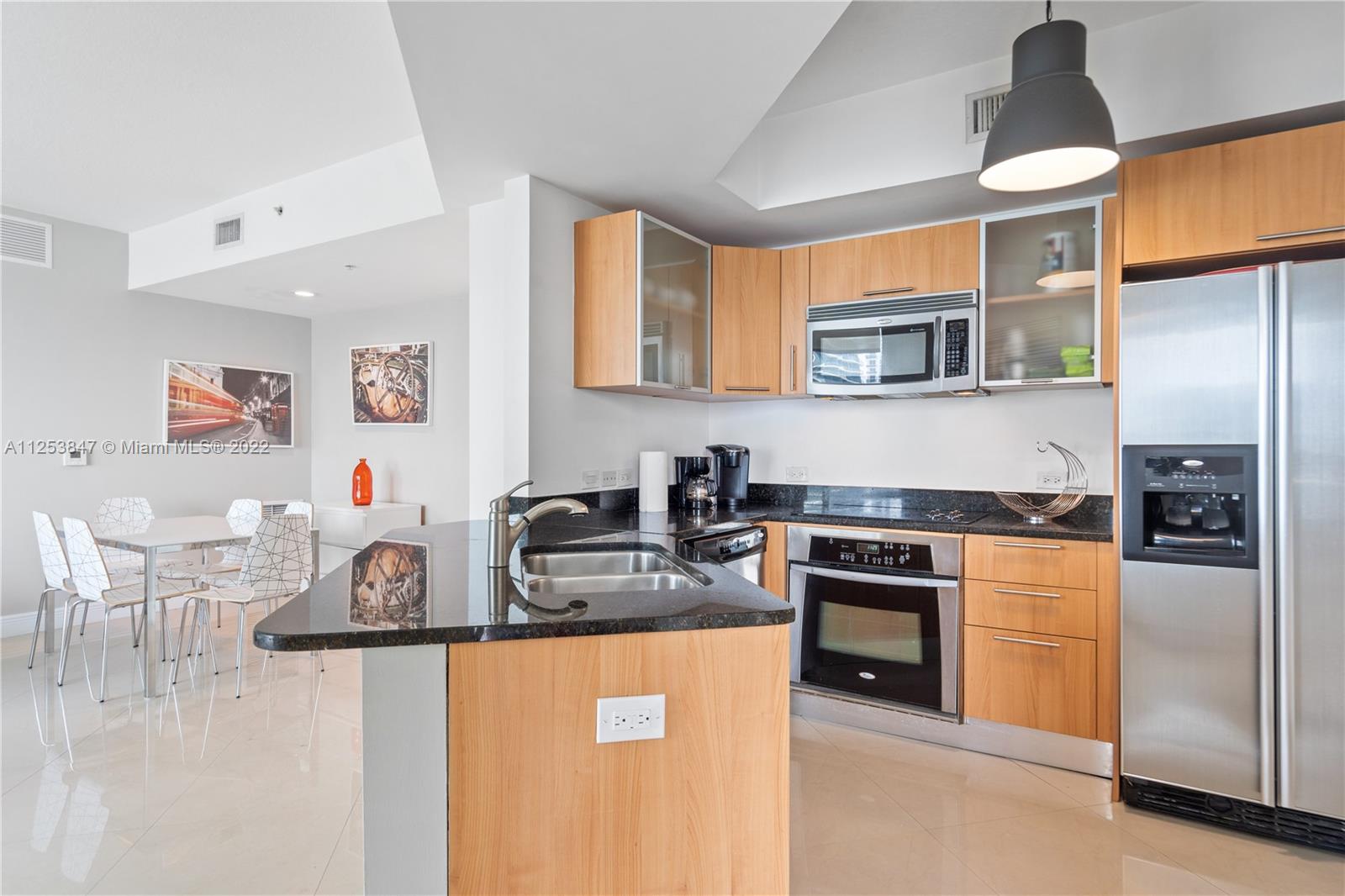 480 Northeast 30th Street, Unit 2003 Miami, FL 33137 - Photo 5 of 17 a kitchen with stainless steel appliances granite countertop a stove top oven a sink a dining table and chairs with wooden floor