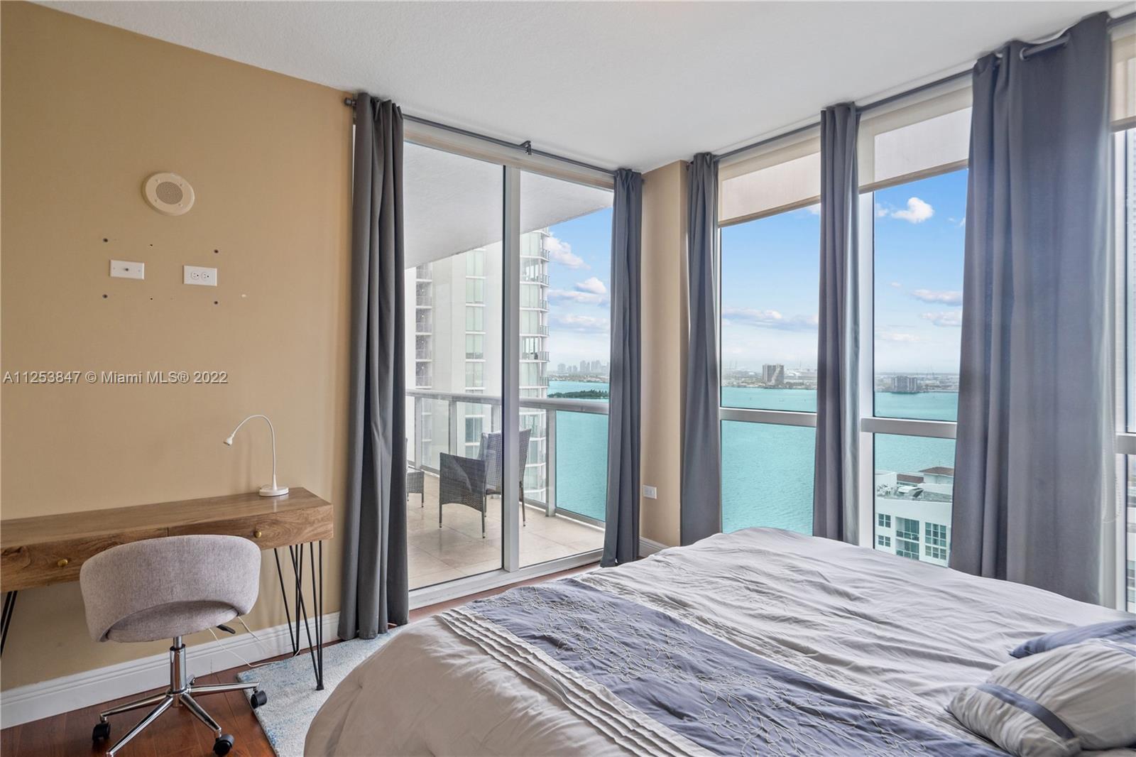 480 Northeast 30th Street, Unit 2003 Miami, FL 33137 - Photo 9 of 17 a bedroom with a bed and glass door