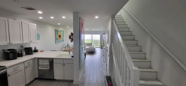 a kitchen with white cabinets and sink