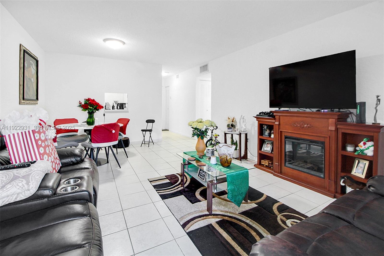 7700 Camino Real, Unit D101 Miami, FL 33143 - Photo 6 of 13 a living room with furniture a flat screen tv and a fireplace
