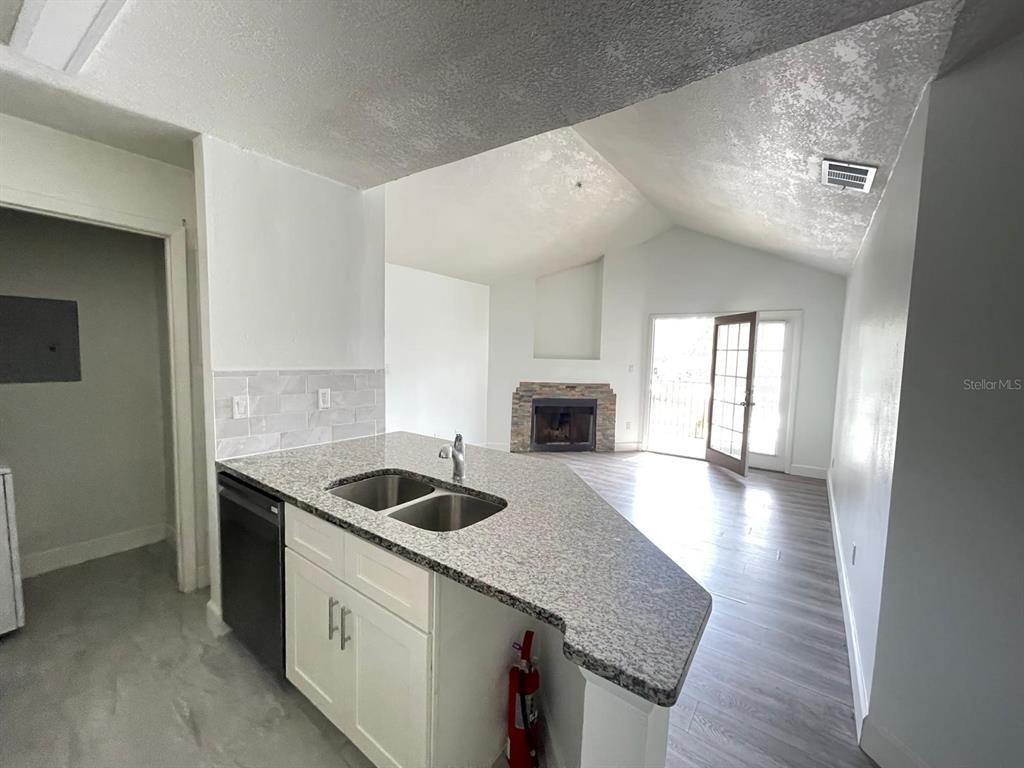 236 Afton Square, Unit 305 Altamonte Springs, FL 32714 - Photo 20 of 30 a kitchen with granite countertop a sink and white cabinets with wooden floor