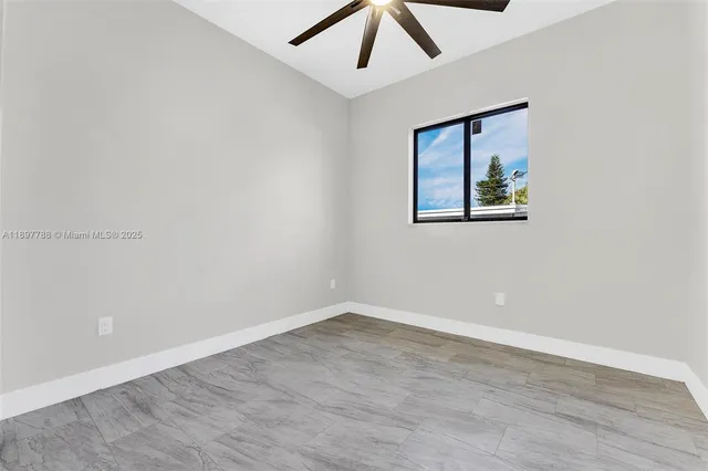 an empty room with a window and ceiling fan