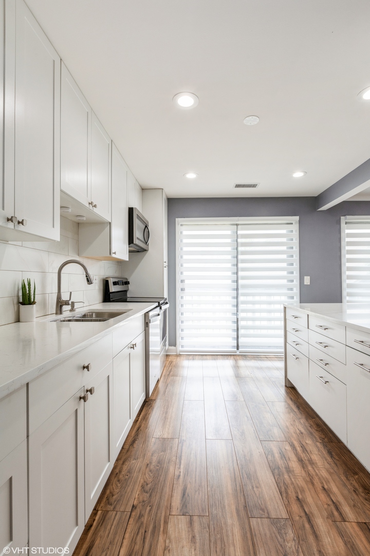 232 Stanhope Drive, Unit C Willowbrook, IL 60527 - Photo 4 of 12 a kitchen with wooden floors and white cabinets