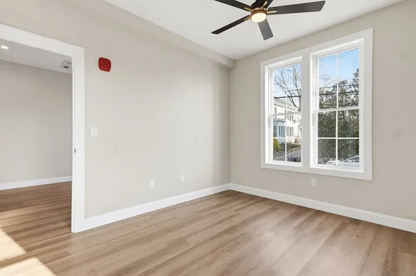 a view of an empty room with a window and wooden floor