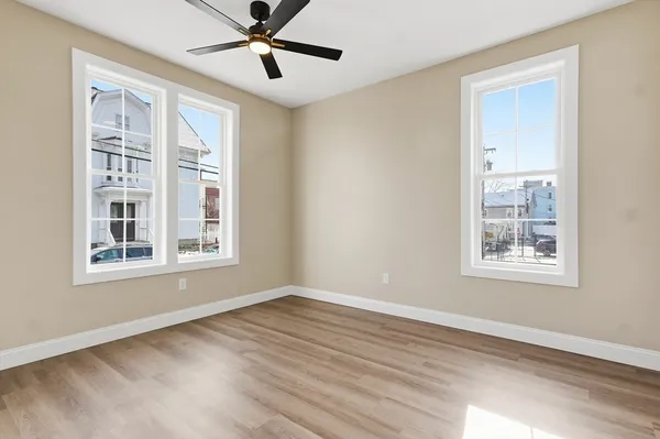 an empty room with wooden floor and windows