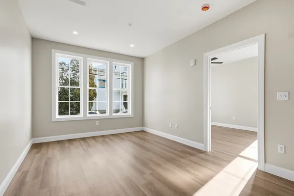 an empty room with wooden floor and windows