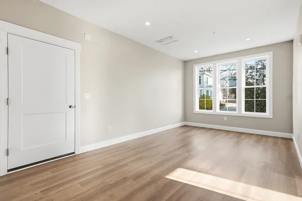 a view of an empty room with wooden floor and windows