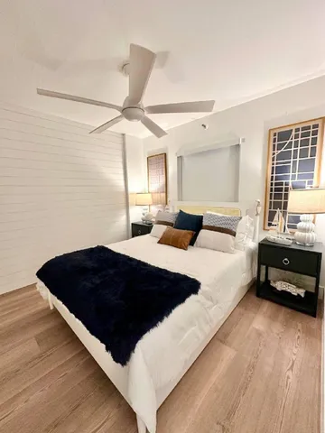 a view of an empty room with wooden floor and kitchen view