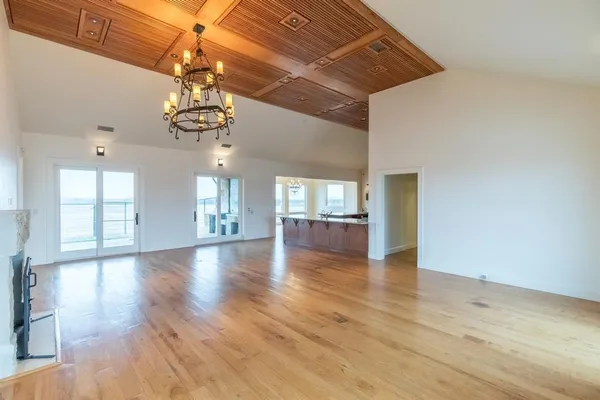a view of a livingroom with a chandelier fan and wooden floor