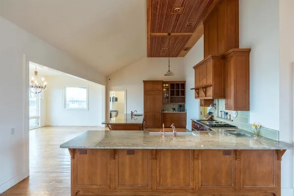 a kitchen with kitchen island granite countertop a sink and a wooden cabinets