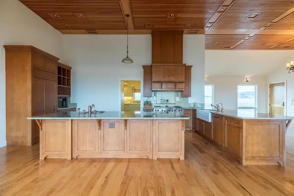 a view of a kitchen with kitchen island granite countertop wooden floors and a sink