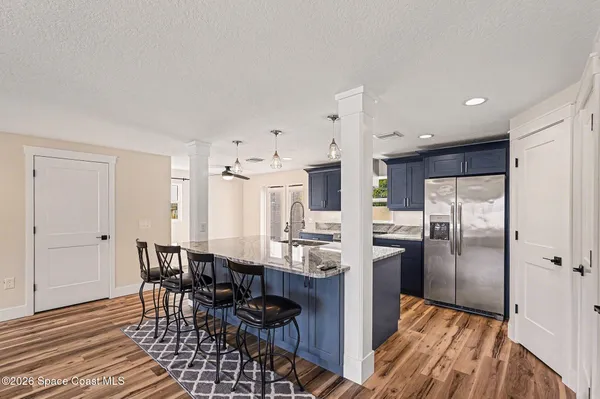 a kitchen with stainless steel appliances a refrigerator a stove a sink and white cabinets with wooden floor