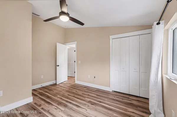 a view of a room with wooden floor and ceiling fan