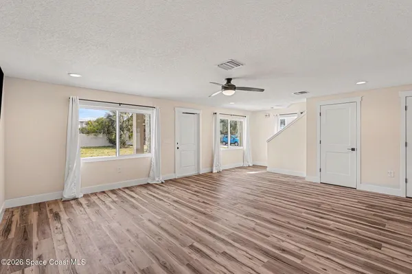 a view of an empty room with a window and wooden floor