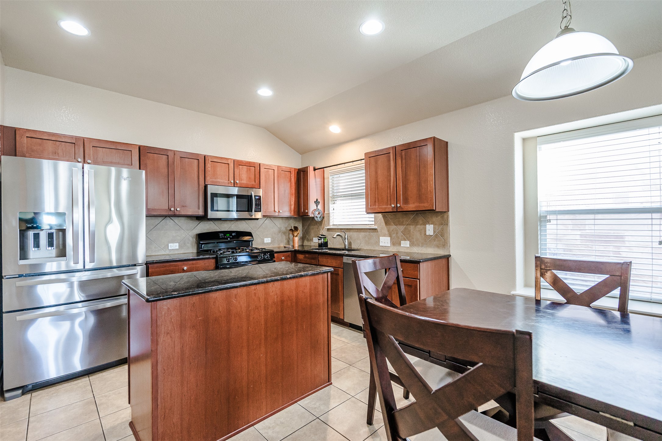 2404 Christoff Loop Austin, TX 78748 - Photo 23 of 24 a kitchen with stainless steel appliances granite countertop a refrigerator a sink dishwasher a stove top oven a kitchen island and chairs with wooden floor